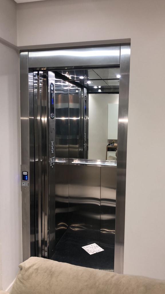 Cabine de elevador em aço inox com porta aberta